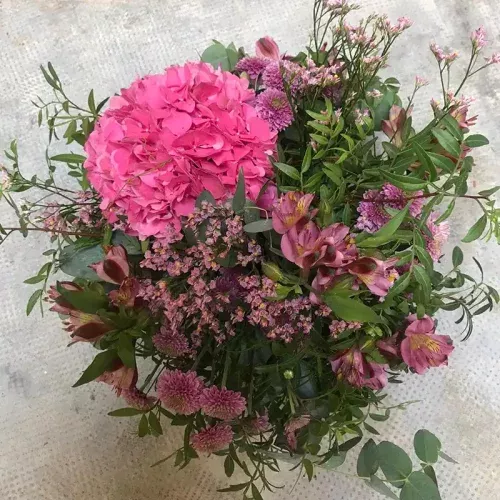 Centro de mesa floral en tonos rosas y lilas con flores variadas