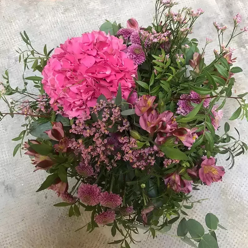 Centro de mesa floral en tonos rosas y lilas con flores variadas